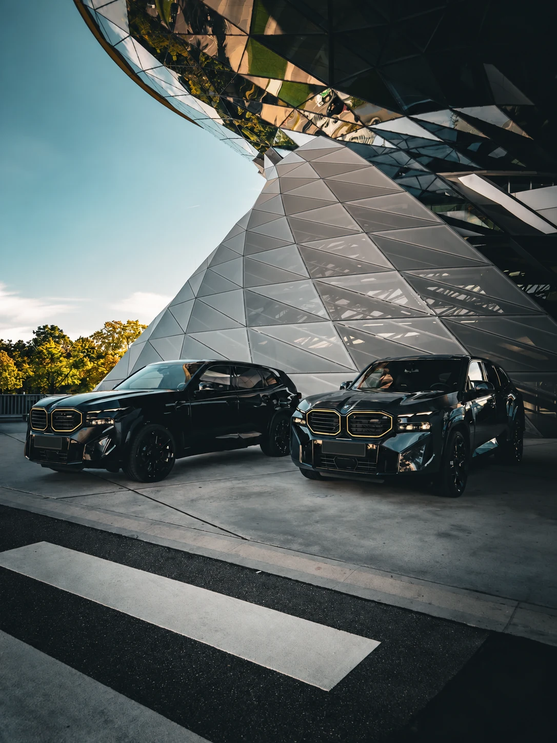 Zwei BMW XM vor moderner Architektur