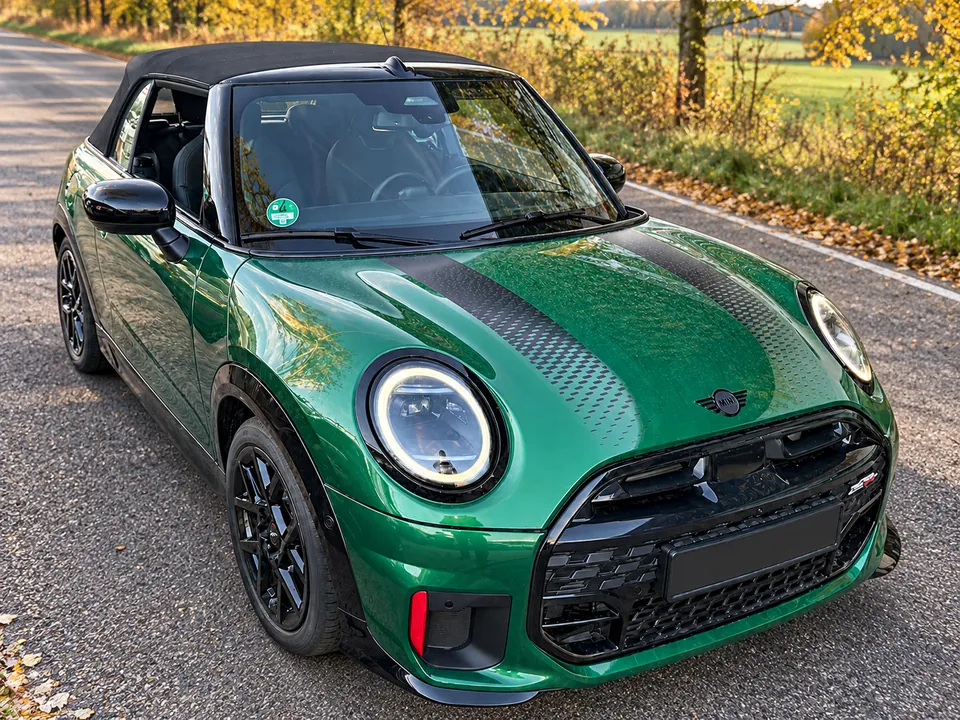 Grüner MINI Cabrio JCW auf einer herbstlichen Landstraße, schräge Frontansicht
